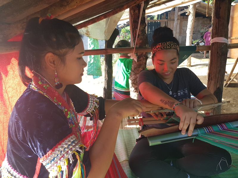 Tribal woman teaching student to weave